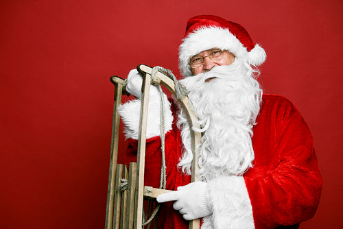 Caucasian Santa Claus with sled on red background