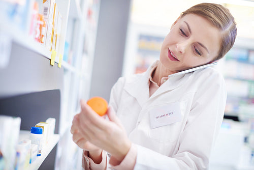 Female pharmacist on phone call reaching medication