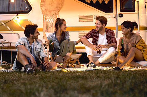 Group of young friends spending time on the camping side, drinking beer and chatting