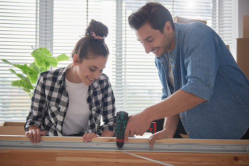 Couple using electronic drill to install a bed