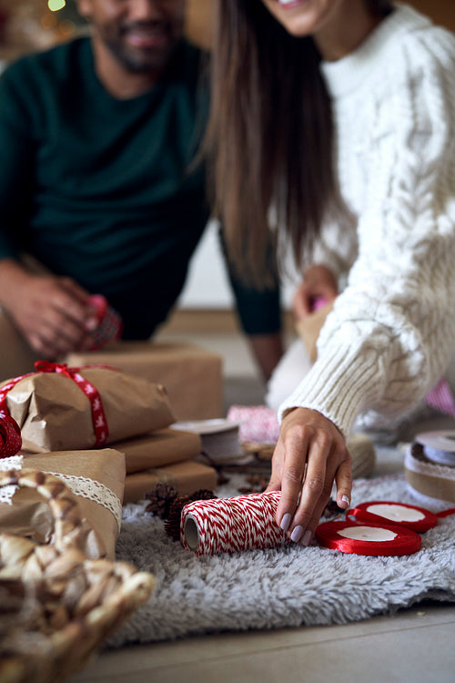 Couple choosing ribbon for Christmas present at home