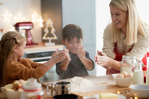 Children clasping using flour while baking cookies