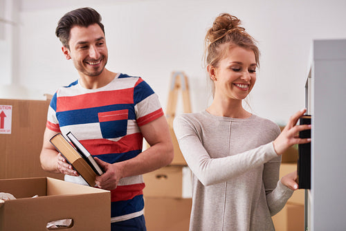 Young couple unpacking moving boxes in new flat