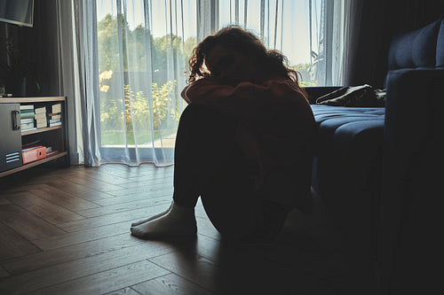 Depressed young caucasian woman flooring in silence in dark room