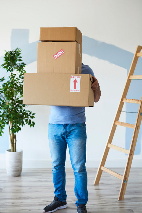 Man holding stack of boxes in front of his face