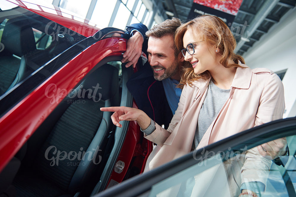 Adult couple admiring car in the showroom