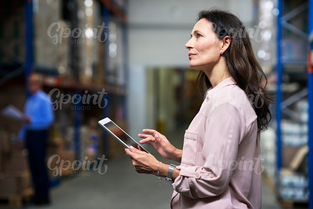 Caucasian woman working in the warehouse and holding digital tablet 