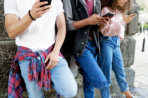 Close up of unrecognizable young people standing with mobile phones