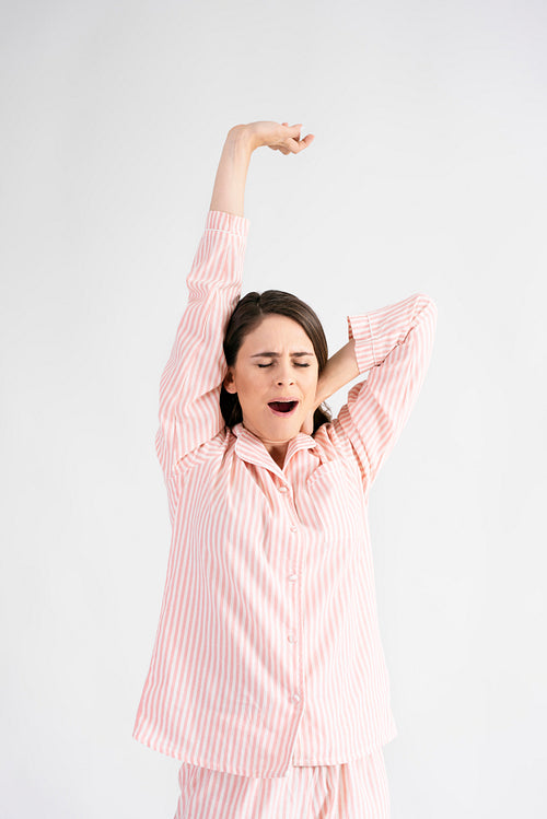 Young woman stretching and yawning in studio shot
