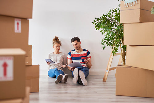 Worried couple examining expenses next to moving boxes