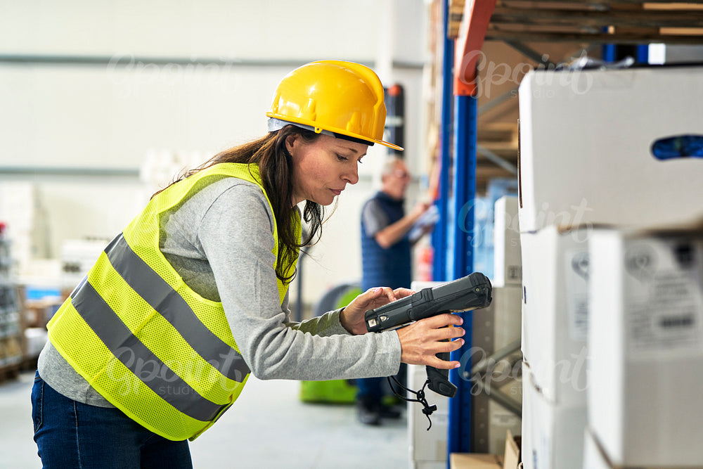 Adult caucasian woman using bar code reader in a warehouse
