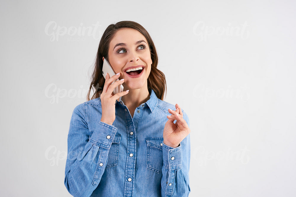 Happy, young woman using mobile phone in studio shot