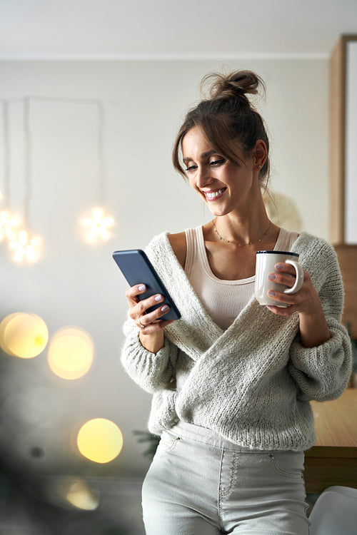 Caucasian woman with cup and mobile phone in Christmas time