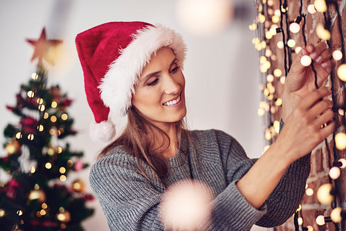 Woman hanging christmas lights at home