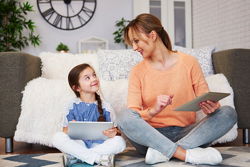 Young mom and her daughter using a tablet in living room
