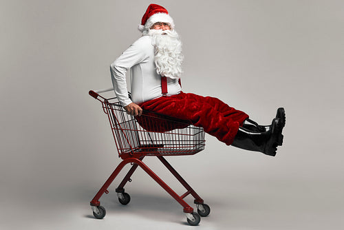 Caucasian Santa Claus sitting in shopping cart