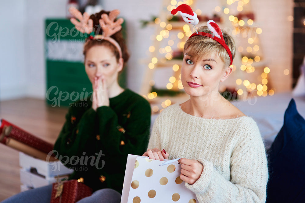 Portrait of displeased girl opening christmas present