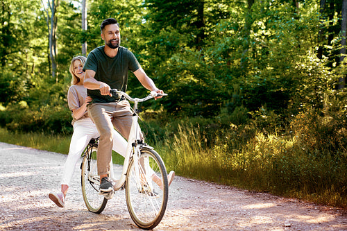 Playful couple having fun on a bike in the forest