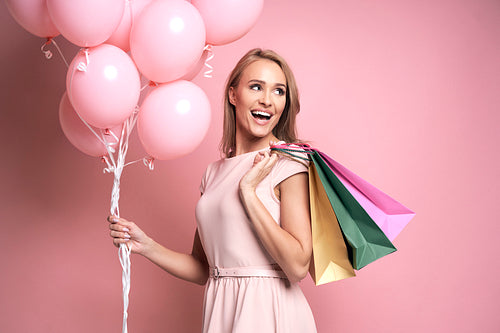 Studio shot of caucasian young woman with shopping bags and pink balloons