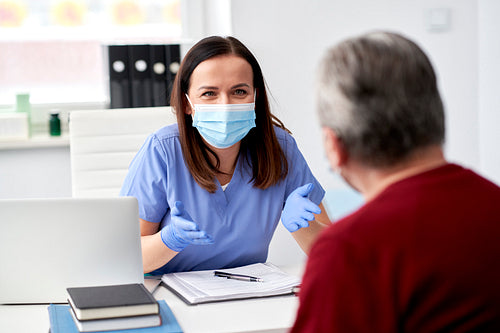 Female doctor in protective mask talking with a patient