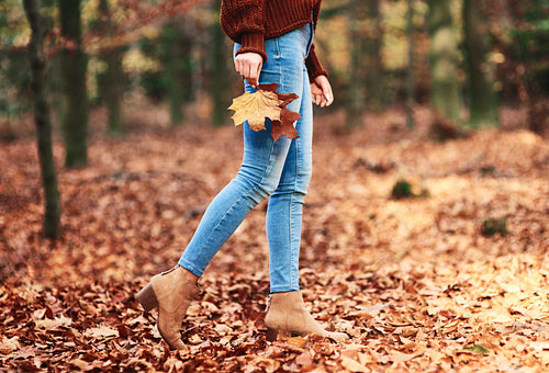Low section of woman walking in autumn forest