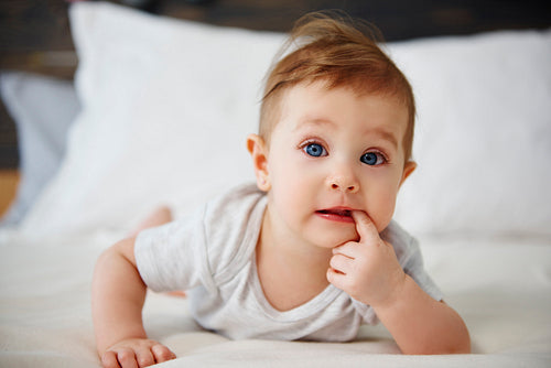Portrait of confused baby lying on the bed