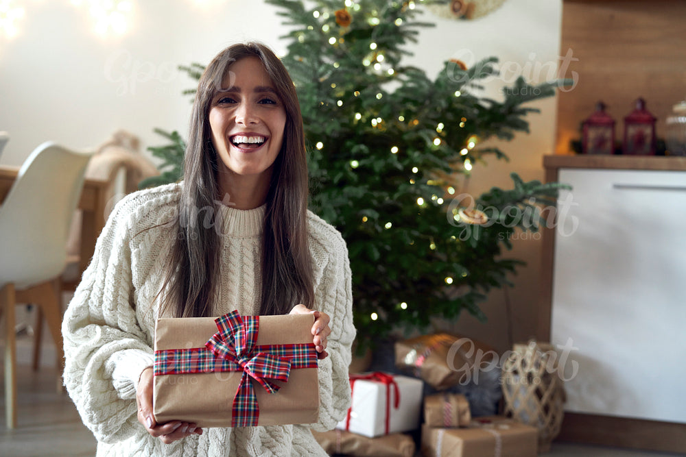 Portrait of smiling caucasian woman with Christmas gift at home 