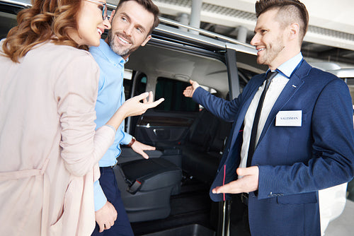 Salesman showing couple the car in showroom