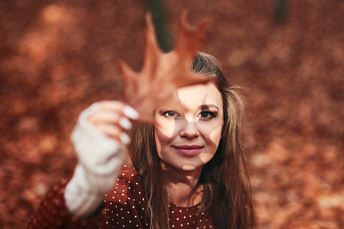 Woman with leaf shadow on face in the autumn forest
