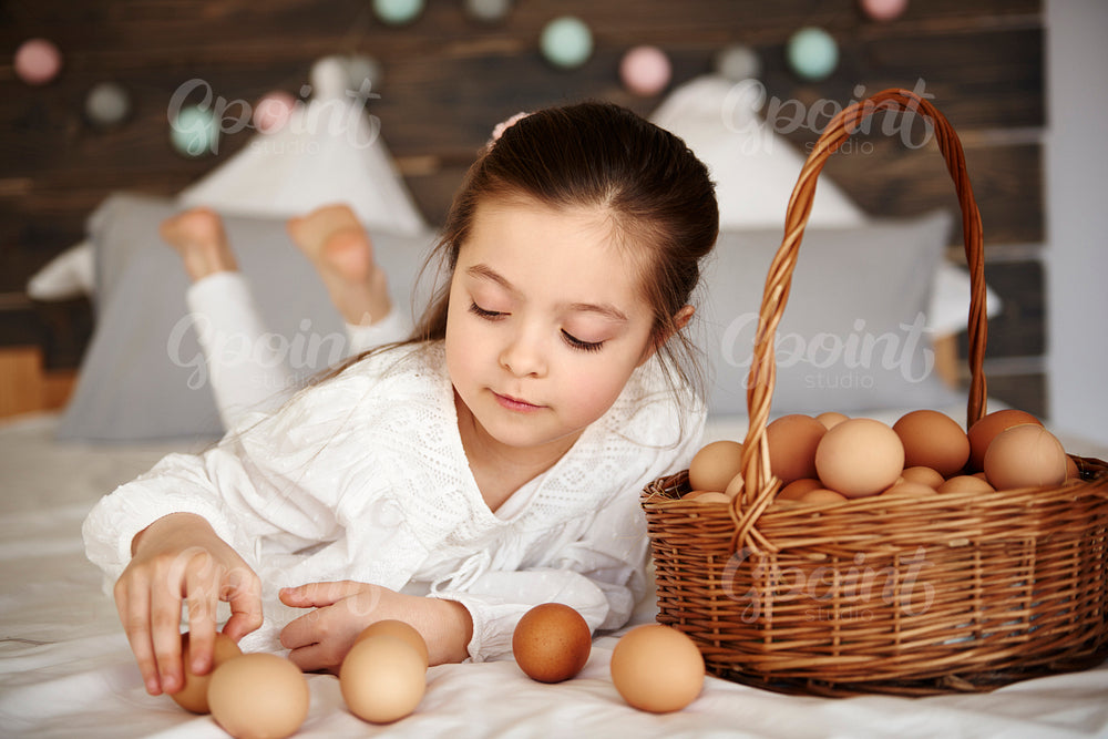 Girl having fun with eggs in bed