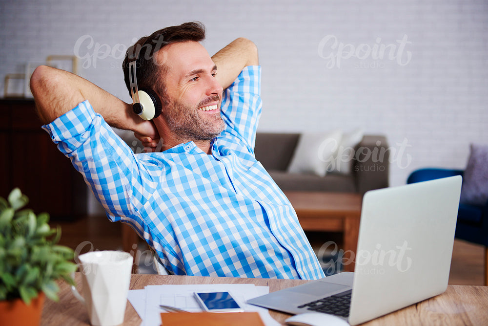 Satisfied man resting and listening to music in his office