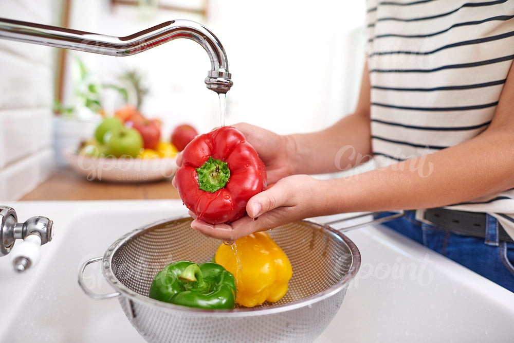 Woman washing colorful peppers