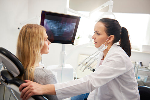 Dentist talking to young woman during dental checkup