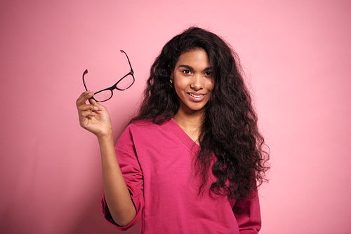 Beautiful African woman holding eyeglasses in hand in studio shot.