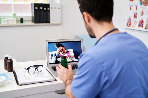 Rear view of doctor during video conference with sick patient