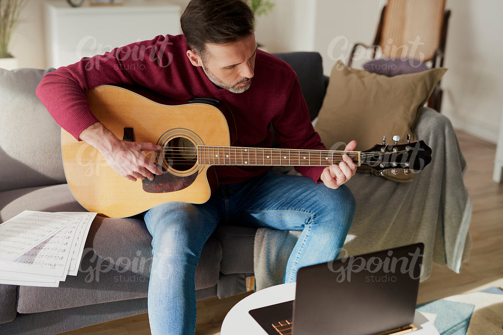 Man having a home course of guitar play