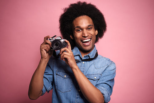 Portrait of a smiling man with camera in studio shot.