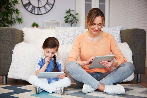 Girl and her mom using a tablet in living room