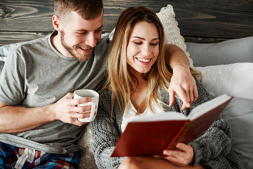 Young couple reading book at bedroom