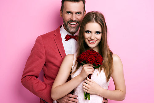 Portrait of man embracing woman with bunch of roses