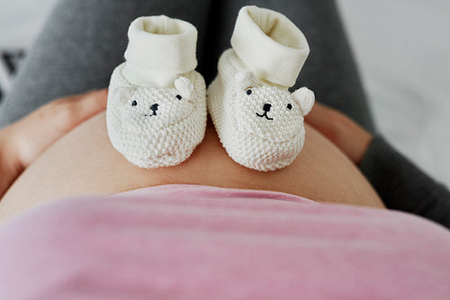 Baby shoes on pregnant abdomen of future mom