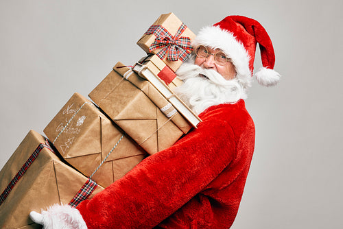 Caucasian Santa Claus holding stack of Christmas presents