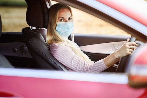 Woman driving a car wearing a protective mask
