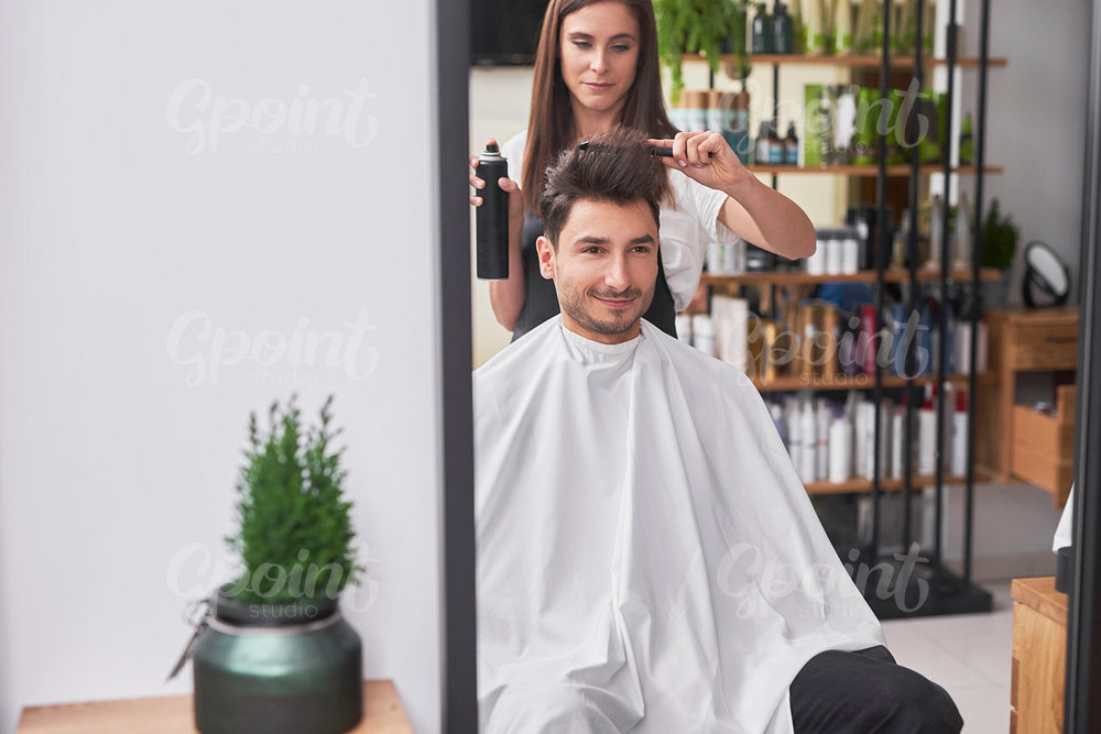 Female hairdresser  is creating trendy hairstyle her male customer