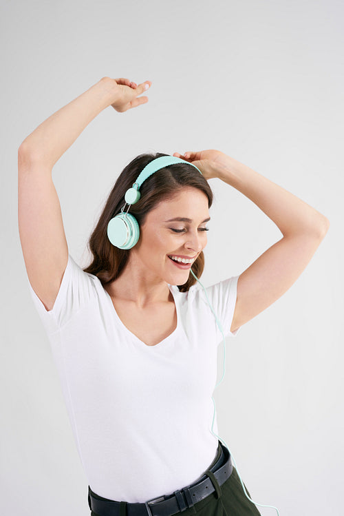 Beautiful woman in headphones listening to music and dancing