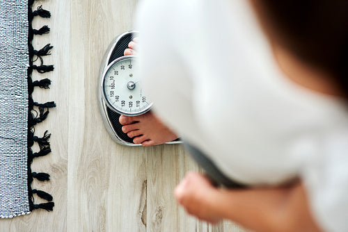 Horizontal image of woman standing on a bathroom scale