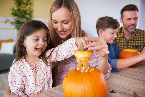 Children carving pumpkins with parents for Halloween