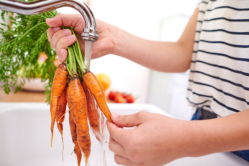 Woman washing fresh and organic carrots