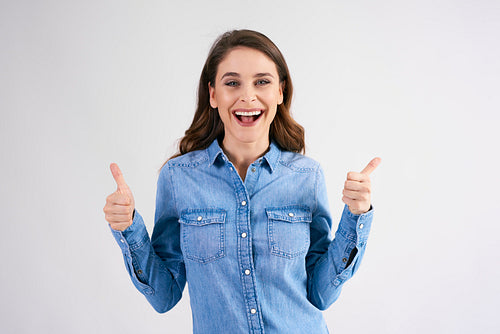 Portrait of excited woman with thumbs up in studio shot